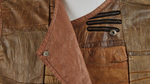 Detail of the neck line of a leather patchwork style brown waistcoat made of different shades of leather gloves.